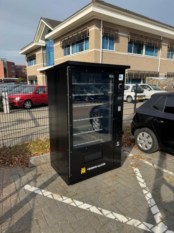 Vendingautomaat op parkeerplaats bij een vliegveld, met snacks en drankjes als 24/7 self service oplossing voor reizigers en bezoekers onderweg