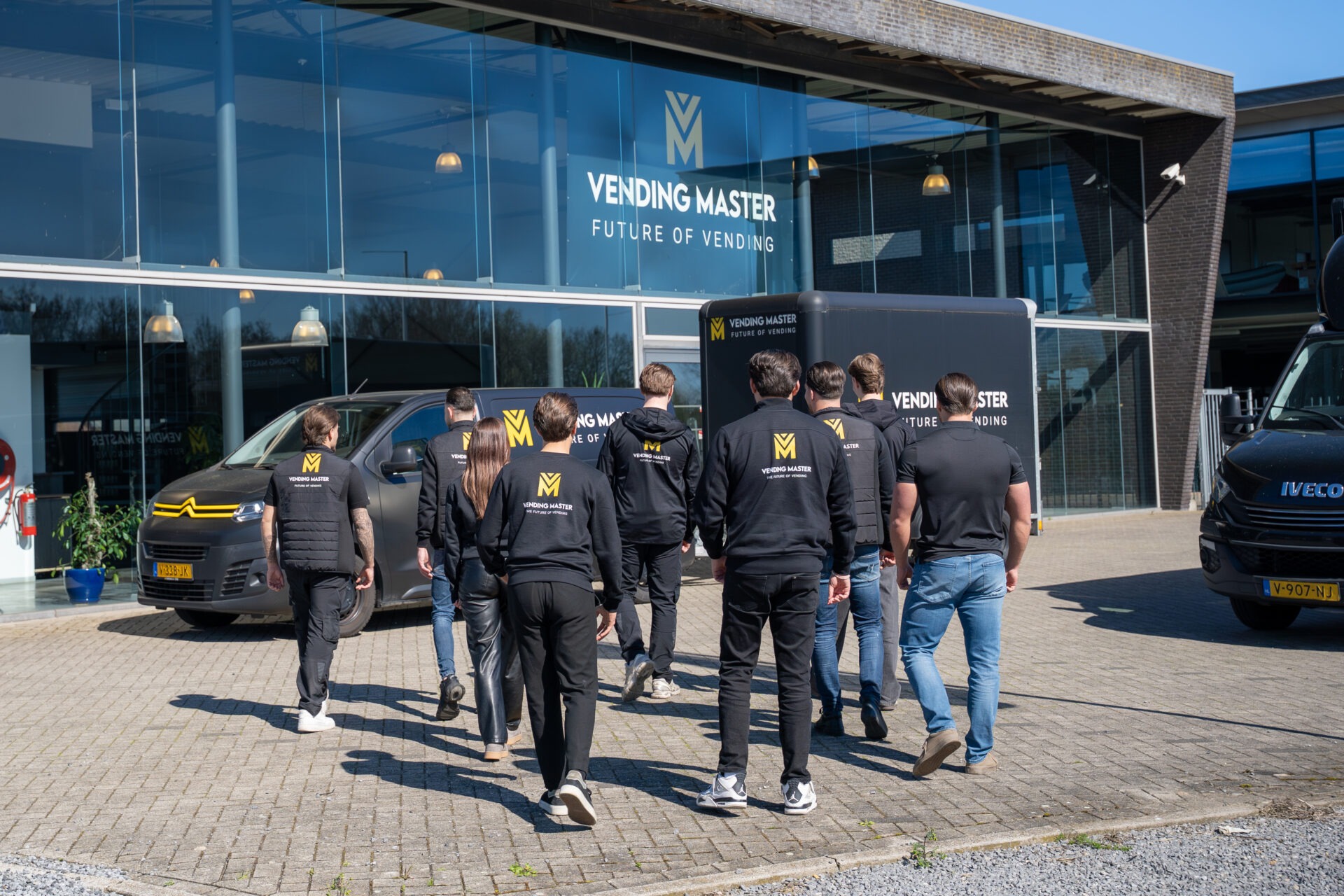 Team van Vending Master loopt richting pand in Cuijk, specialist in vendingmachines, smart vending en onbemande winkels in Nederland, Duitsland, België en Luxemburg